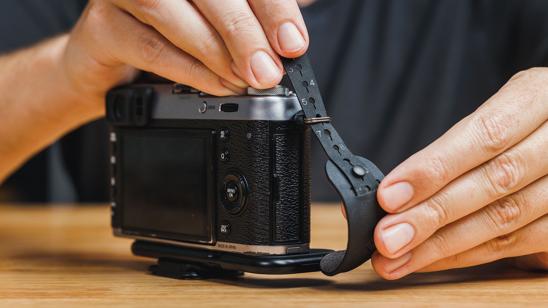 Threading the Peak Design Micro Clutch strap through an eyelet on a Fuji camera